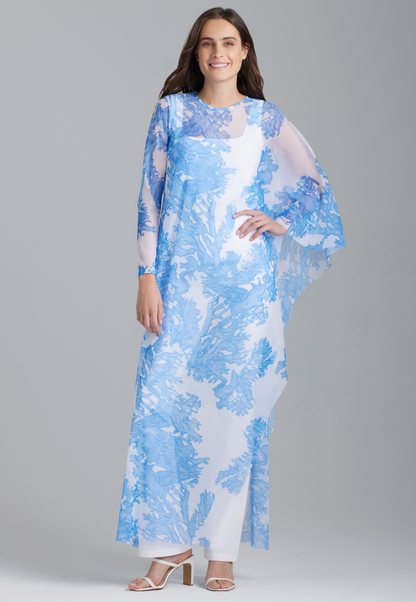 Woman wearing blue coral printed mesh one armed poncho kaftan over white italian stretch cotton tank tops and pants by Ala von Auersperg for summer 2023