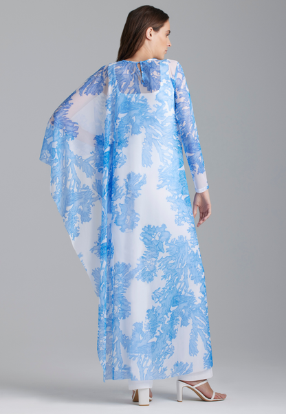 Woman wearing blue coral printed mesh one armed poncho kaftan over white italian stretch cotton tank tops and pants by Ala von Auersperg for summer 2023